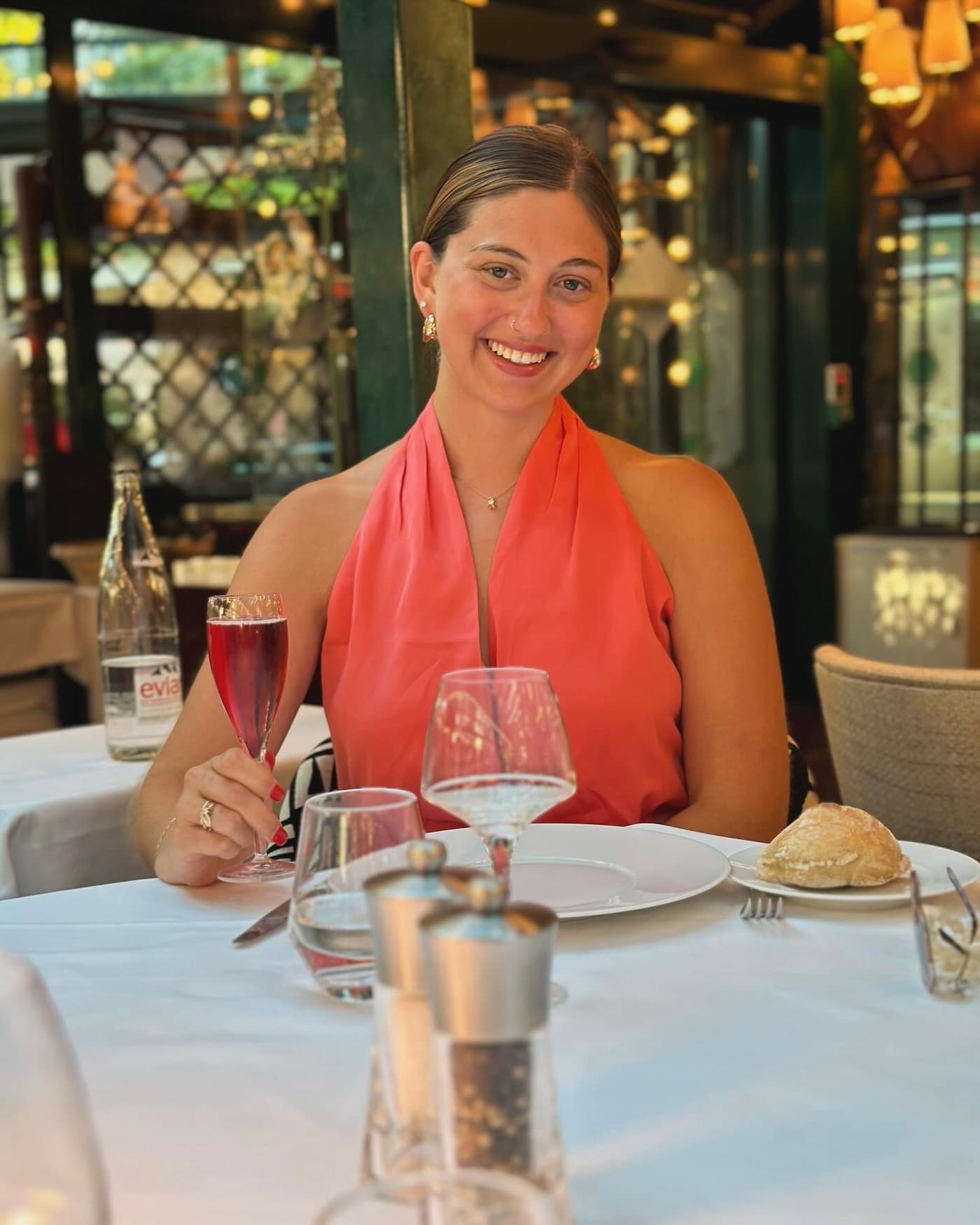 Juliana Margarone at a restaurant table, raising a glass